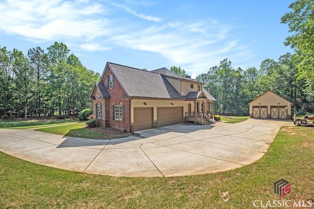 view of home's exterior with a yard, driveway, an outbuilding, brick siding, and roof with shingles