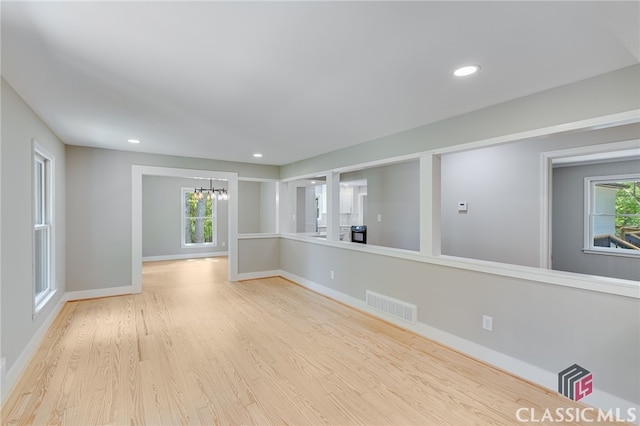 spare room featuring baseboards, a wealth of natural light, an inviting chandelier, and visible vents