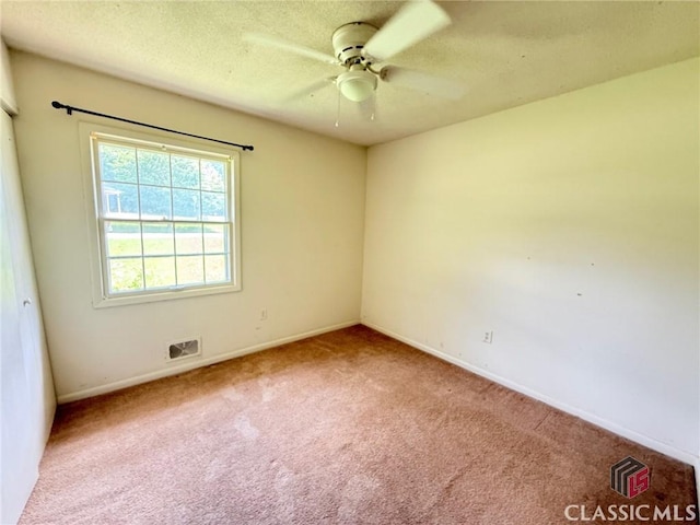 carpeted empty room with ceiling fan, baseboards, and a textured ceiling