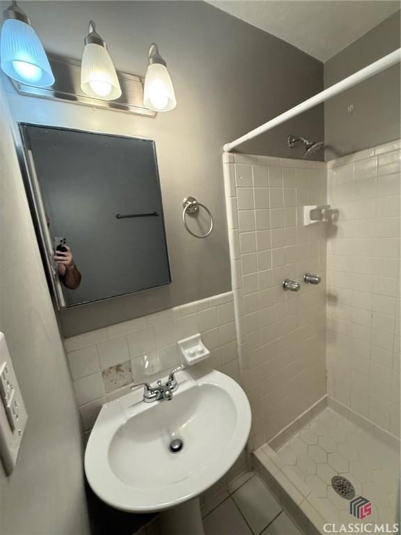 full bathroom featuring a shower stall, a sink, tile patterned floors, and tile walls