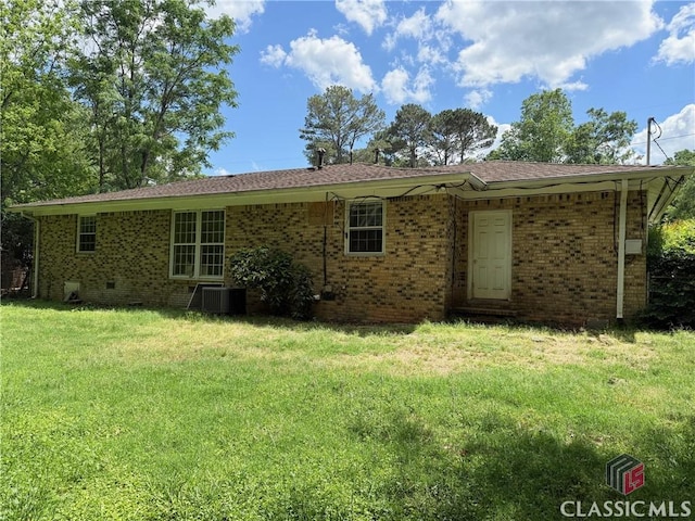 back of house featuring a lawn, brick siding, and cooling unit
