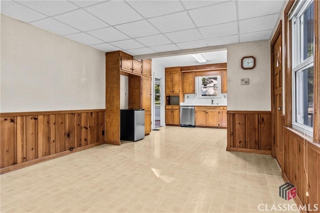120 Mathews Ave, Athens, GA 30606 - kitchen featuring stainless steel appliances, a wainscoted wall, brown cabinets, a drop ceiling, and wooden walls