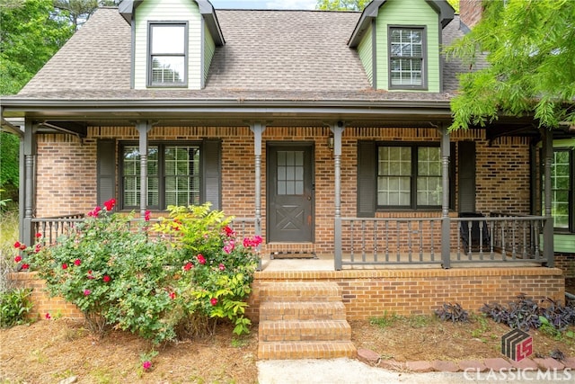 doorway to property featuring a porch and brick siding