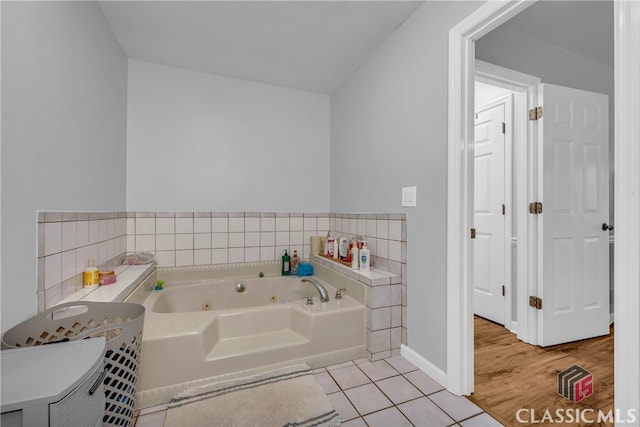 bathroom with a tub with jets, tile patterned flooring, and baseboards