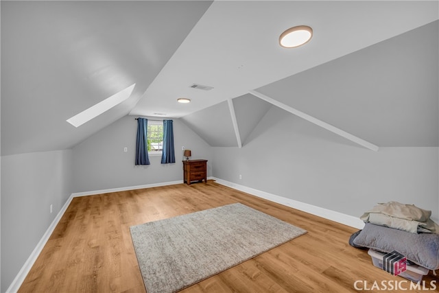 bonus room featuring a skylight, light wood-style floors, baseboards, and vaulted ceiling