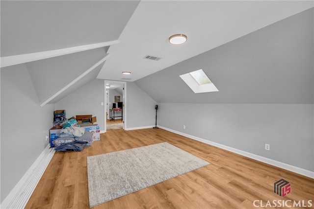 additional living space with a skylight, wood finished floors, baseboards, and lofted ceiling
