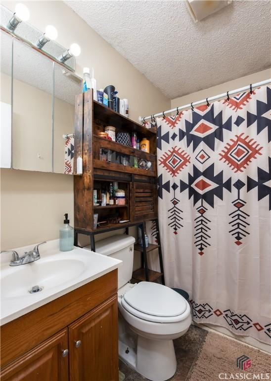 35 Good Hope Rd, Colbert, GA 30628 - bathroom featuring a textured ceiling, toilet, vanity, and a shower with shower curtain
