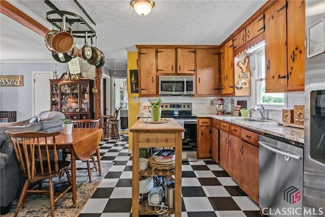 3081 Macedonia Rd, Union Point, GA 30669 - kitchen featuring appliances with stainless steel finishes, dark flooring, a sink, brown cabinets, and crown molding