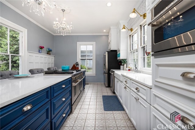 172 N Second St, Madison, GA 30650 - kitchen with stainless steel appliances, blue cabinetry, a chandelier, light countertops, and white cabinets