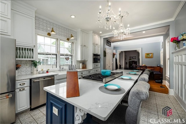172 N Second St, Madison, GA 30650 - kitchen featuring stainless steel appliances, a kitchen island, crown molding, a chandelier, and decorative backsplash