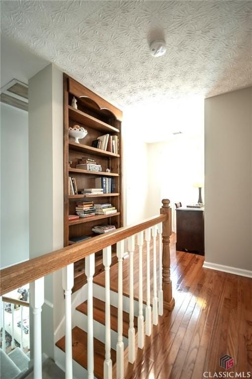 1181 Pete Dickens Rd, Bogart, GA 30622 - hall featuring hardwood / wood-style floors, an upstairs landing, baseboards, and a textured ceiling