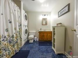 256 Cherokee Rdg, Athens, GA 30606 - full bathroom with stacked washer and clothes dryer, toilet, vanity, a shower with shower curtain, and tile patterned flooring