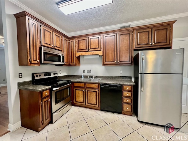 kitchen with appliances with stainless steel finishes, a sink, dark countertops, crown molding, and light tile patterned floors