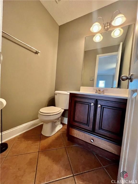 bathroom with tile patterned floors, vanity, baseboards, and toilet