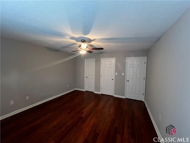 unfurnished bedroom featuring dark wood-style flooring, baseboards, and a textured ceiling