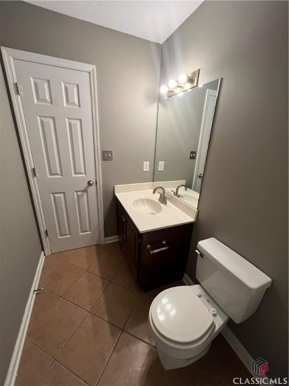half bath with tile patterned flooring, vanity, and baseboards