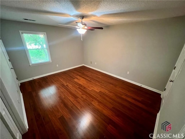 unfurnished bedroom with dark wood-type flooring, a textured ceiling, baseboards, and ceiling fan