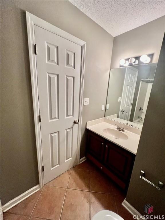 bathroom featuring tile patterned floors, a textured ceiling, vanity, and baseboards