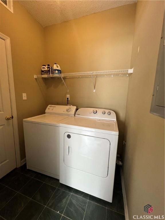washroom with washer and dryer, a textured ceiling, and dark tile patterned flooring