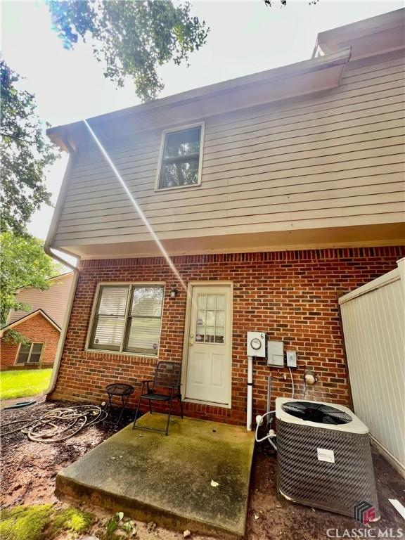 rear view of house featuring brick siding and central air condition unit