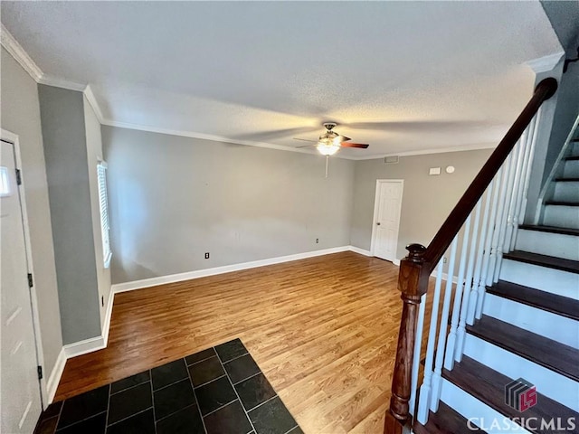 entrance foyer featuring ceiling fan, crown molding, wood finished floors, stairway, and baseboards