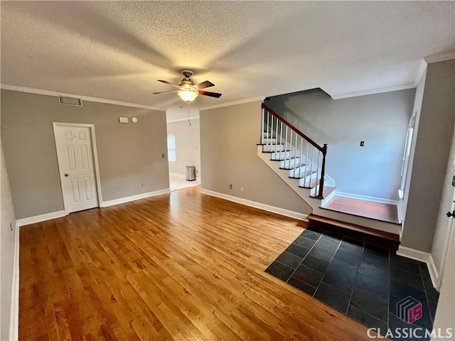 foyer with a ceiling fan, ornamental molding, wood finished floors, stairway, and a textured ceiling