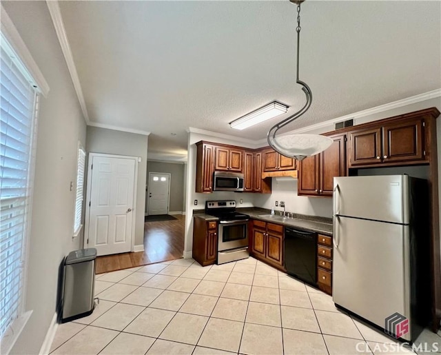 kitchen featuring stainless steel appliances, dark countertops, light tile patterned flooring, a sink, and healthy amount of natural light
