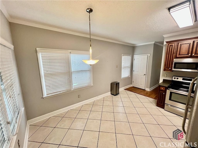 kitchen with appliances with stainless steel finishes, plenty of natural light, ornamental molding, light tile patterned flooring, and dark countertops