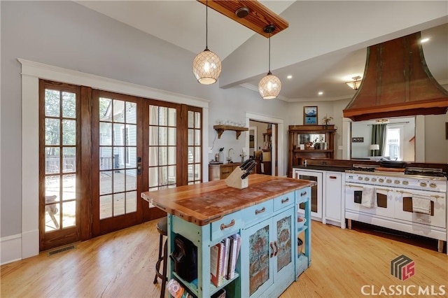 kitchen featuring butcher block counters, open shelves, premium range hood, range with two ovens, and lofted ceiling