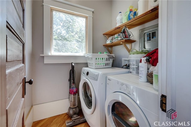 laundry room featuring washing machine and dryer, healthy amount of natural light, and light wood finished floors