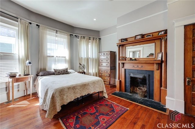 bedroom with a fireplace, wood finished floors, and recessed lighting