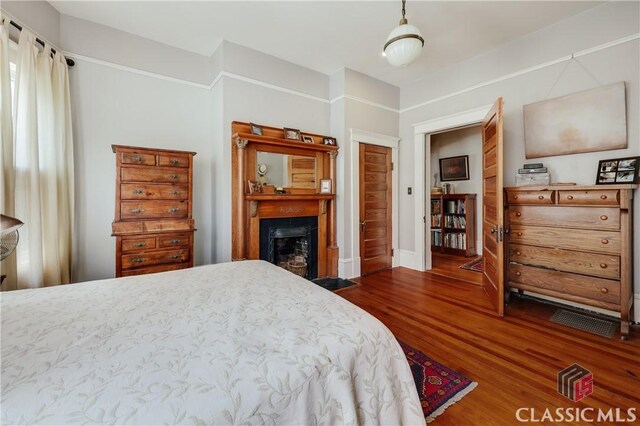 bedroom featuring dark wood-style floors, a fireplace, and baseboards