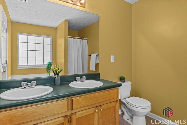 full bath with toilet, double vanity, tile patterned flooring, a textured ceiling, and baseboards