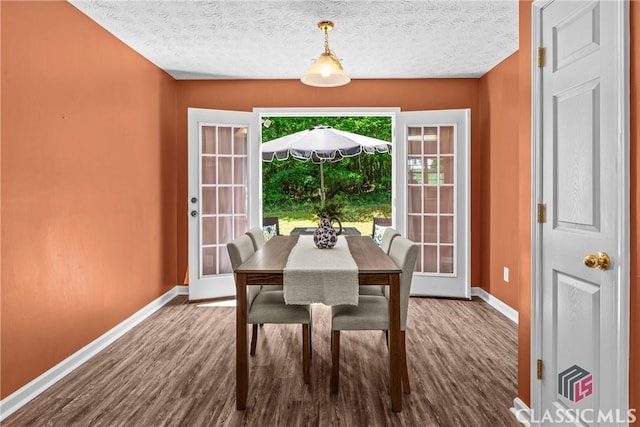 dining area featuring dark wood-style floors, baseboards, and a textured ceiling