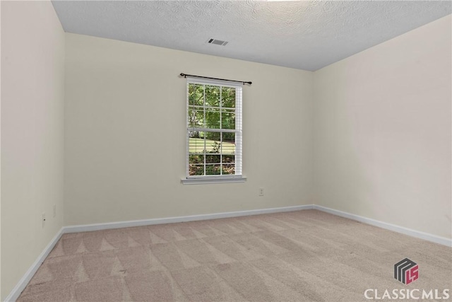unfurnished room with light colored carpet, a textured ceiling, and baseboards