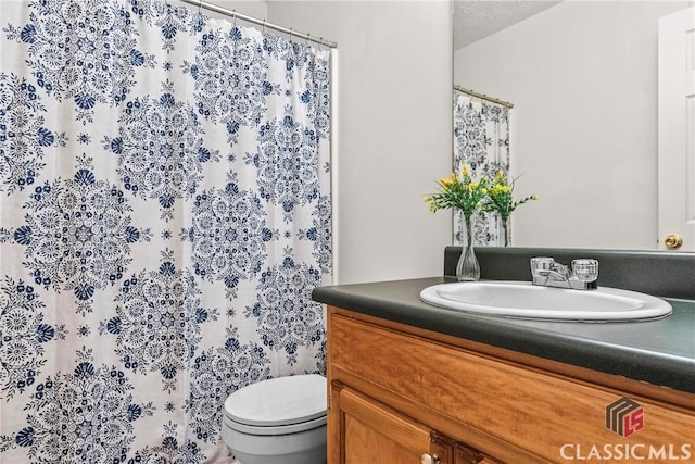 bathroom featuring toilet, vanity, and a shower with shower curtain