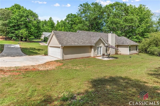 view of front of home with french doors, a front lawn, a chimney, an attached garage, and concrete driveway