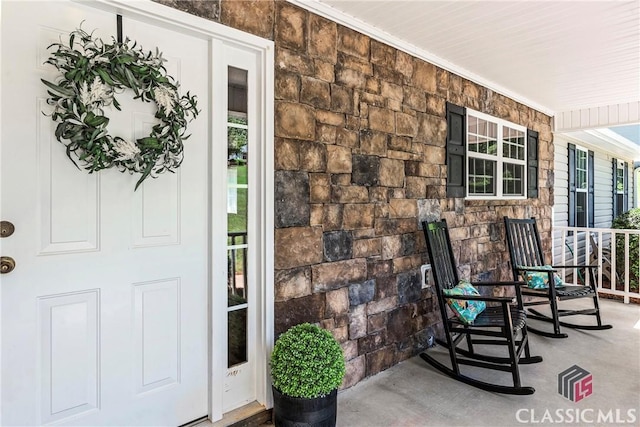 doorway to property with a porch and stone siding
