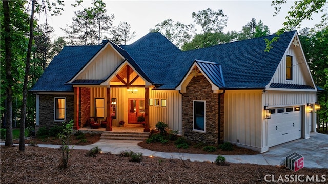 view of front of house with stone siding, a porch, roof with shingles, and driveway