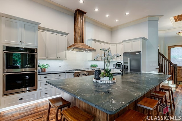 kitchen with high quality fridge, double oven, wood finished floors, a sink, and recessed lighting