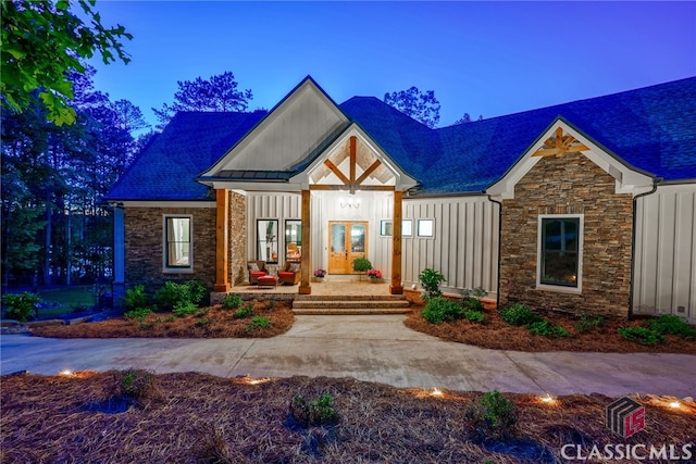 view of front facade featuring stone siding, covered porch, and board and batten siding