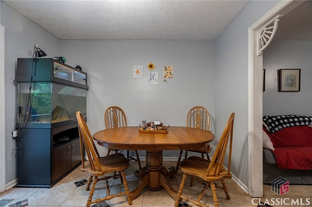 dining room with a textured ceiling, light tile patterned floors, and baseboards