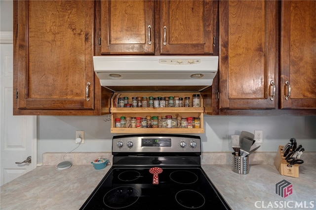 kitchen with under cabinet range hood, stainless steel electric range, light countertops, and open shelves