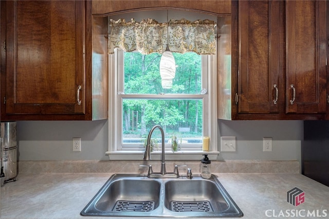 kitchen featuring a sink, light countertops, plenty of natural light, and dark brown cabinets