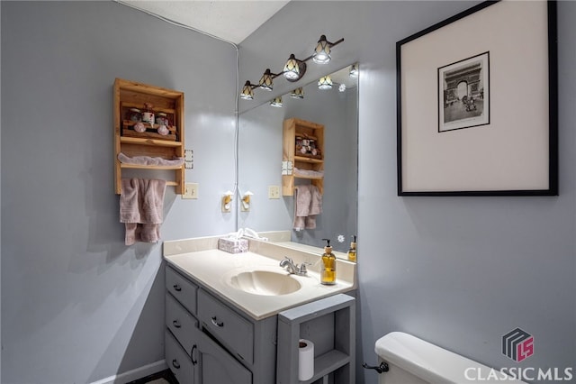 half bathroom featuring vanity, toilet, and baseboards