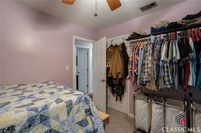 carpeted bedroom featuring a textured ceiling and a ceiling fan