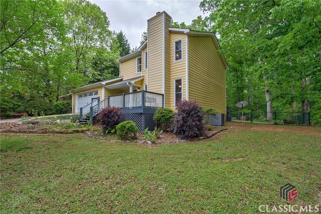 view of front of home featuring a garage, a chimney, cooling unit, and a deck