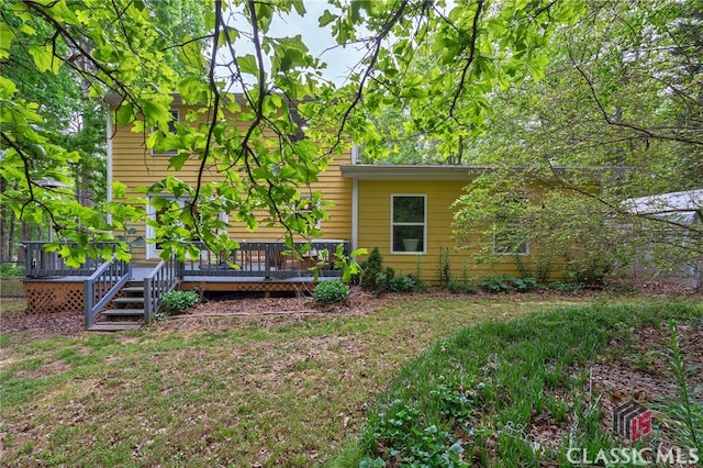 back of property with a deck and a yard