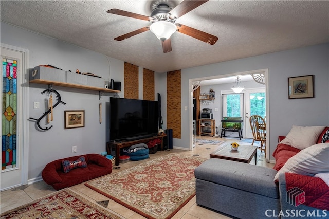living room with a textured ceiling, ceiling fan, light tile patterned flooring, and baseboards