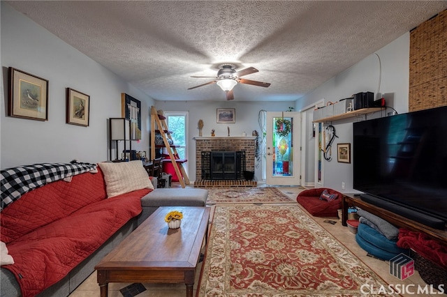 living area featuring ceiling fan, a textured ceiling, and a brick fireplace